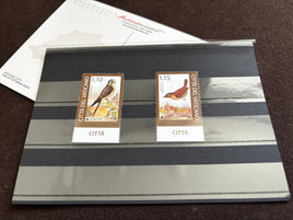 Two vintage Italian civic stamps from Città del Veltano displayed on a striped gray and black presentation card, with a white postmark card in the background.