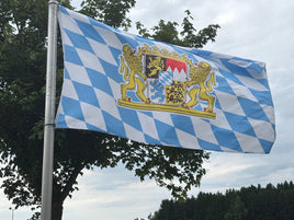 Blue and white checkered flag with a coat of arms against a cloudy sky